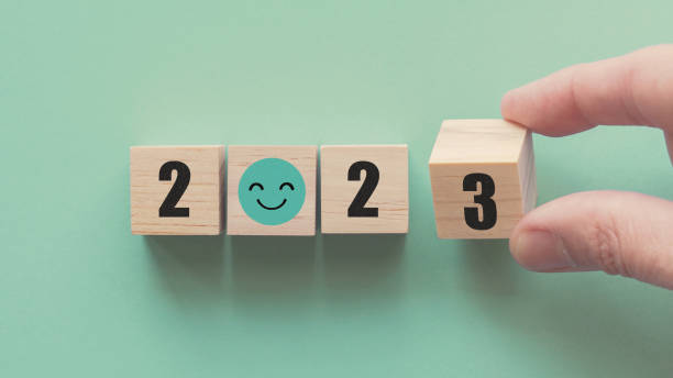 manos sosteniendo 2023 con bloques de madera con cara de sonrisa, feliz año nuevo, plan de salud mental positivo, objetivo de resolución optimista, concepto de objetivo ecosostenible - propósito de año nuevo fotografías e imágenes de stock