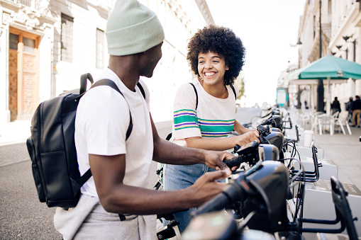 Young African American couple renting e-bikes to explore Madrid.