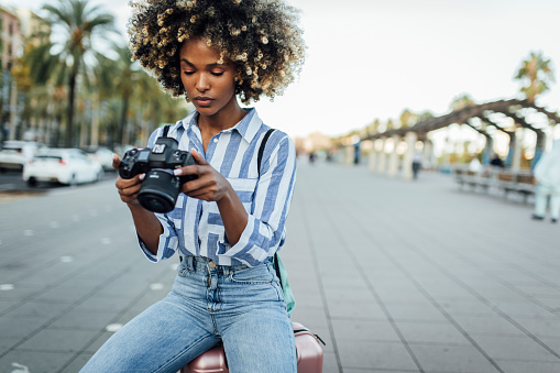 Portrait of a young African American woman on vacation exploring Barcelona and taking a photo.