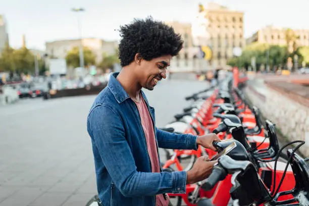 Young African American tourist renting an e-bike to explore Barcelona.