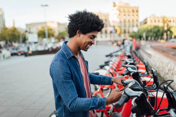 retrato de um jovem turista afro alugando uma e-bike. - bikeshare - fotografias e filmes do acervo