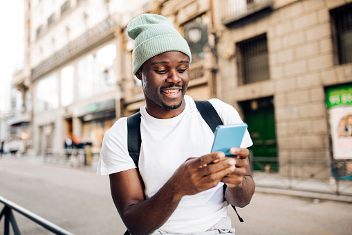 Portrait of a young African American tourist exploring Madrid and using smartphone.