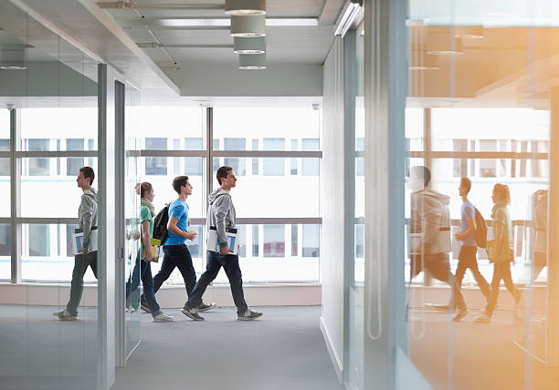 University students walking in corridor  Distant stock pictures, royalty-free photos & images