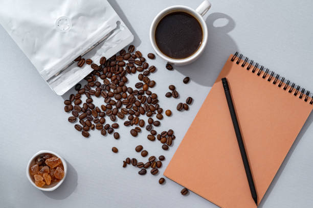 istock Cup of coffee with notebook on gray background top view 1401834153
