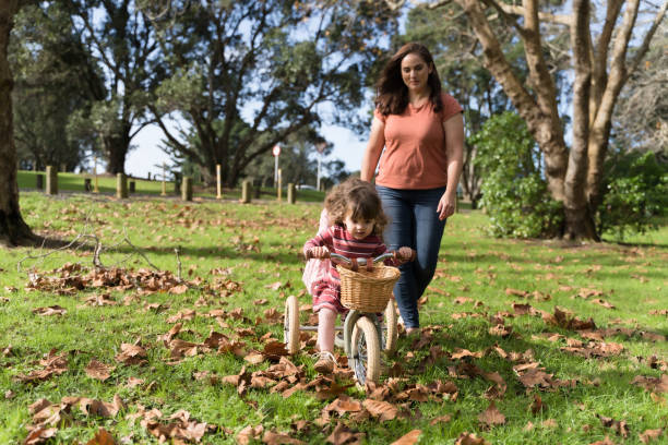 istock Cute kid tricycle ride in park with her mom. 1401835165