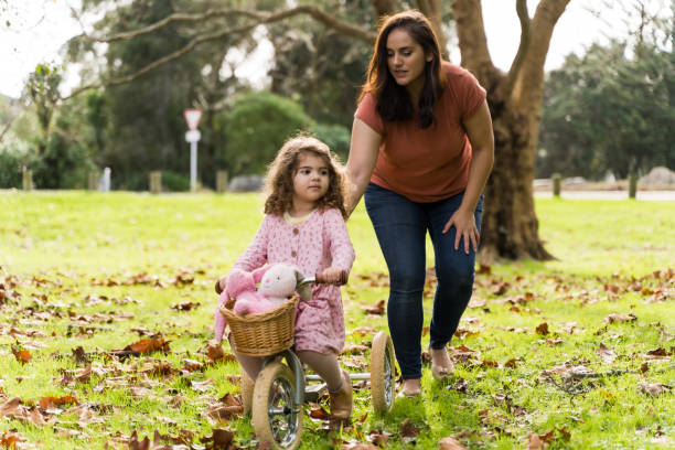istock Riding tricycle in park with her mother. 1401835202