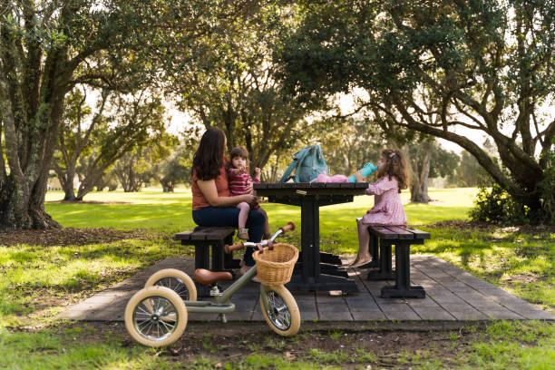 Mother with kids having picnic in park.