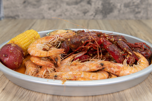 Delicious platter of boiled shrimp, crawfish, corn on the cobb, and potatoes in a buttery sauce for a tasty seafood meal.