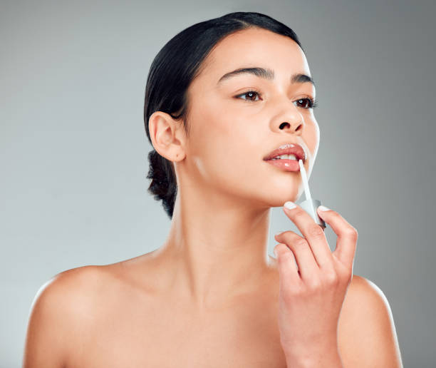 istock A beautiful young mixed race woman with glowing skin posing against grey copyspace background. Hispanic woman applying lipstick in a studio 1401840525