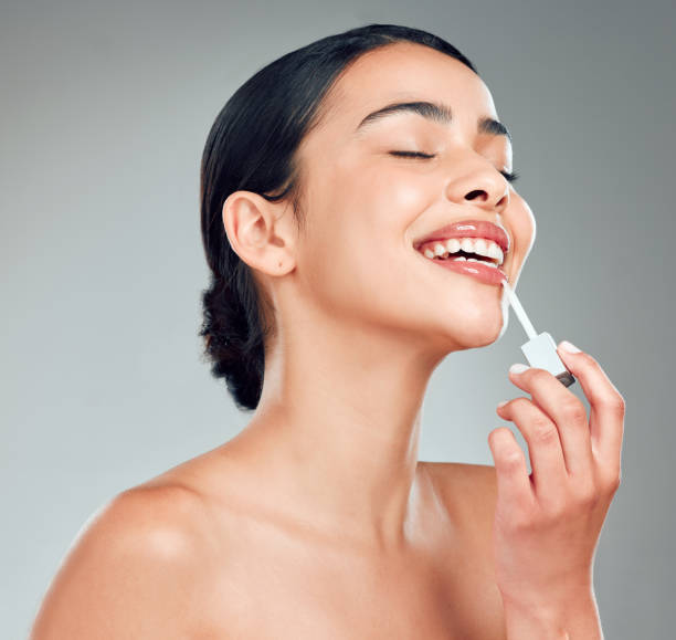 istock A beautiful young mixed race woman with glowing skin posing against grey copyspace background. Hispanic woman applying lipstick in a studio 1401841624