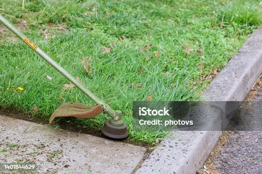 istock Worker cuts the grass with a string trimmer on gasoline 1401844629