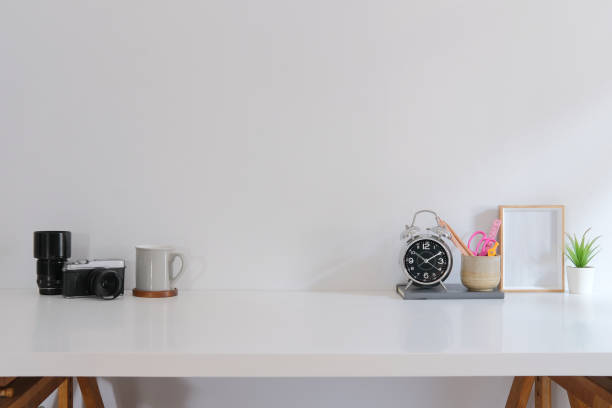 istock Creative workplace with camera, coffee cup, stationery and picture frame on white table. 1401845027