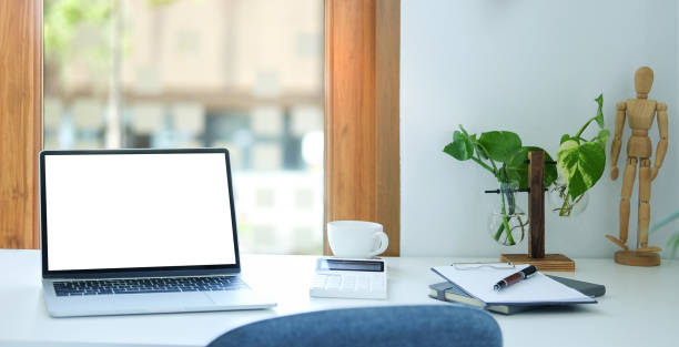 istock Comfortable workplace with laptop computer, coffee cup, notebook and houseplant on white table. 1401845855