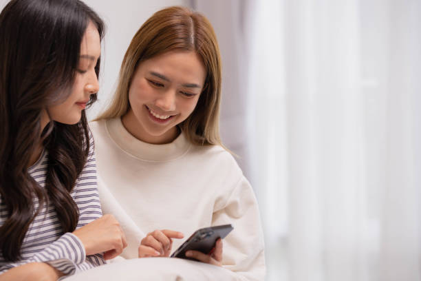 istock Female Couple using digital tablet shopping online and researching online on tablet while sitting on sofa. 1401850268