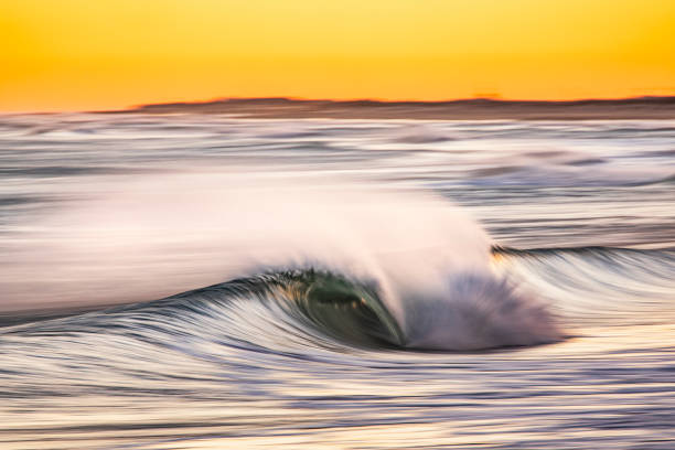 istock Ocean wave with wind spray with bright golden sky at dawn before sunrise 1401856080