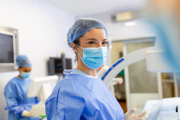 Female surgeon with surgical mask at operating room. Young woman doctor in surgical uniform in hospital operation theater. Female surgeon with surgical mask at operating room. Young woman doctor in surgical uniform in hospital operation theater. intensive care unit stock pictures, royalty-free photos & images