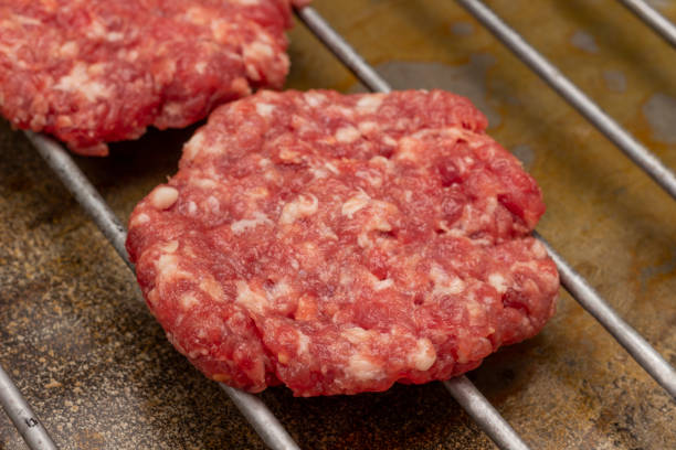 istock Raw beef burgers on grill. 1401866348
