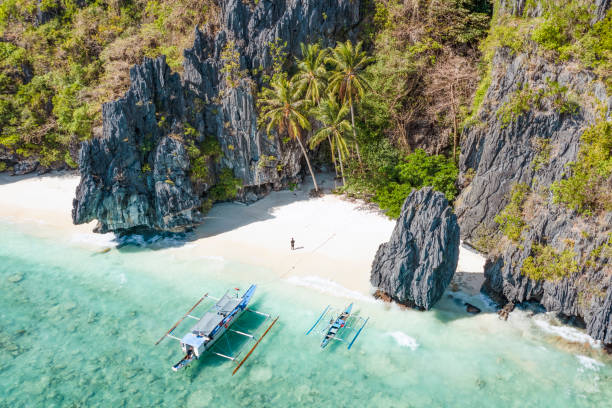 View from above, stunning aerial view of a person on the Entalula Beach, a white sand beach bathed by a crystal clear water. Entalula island, Bacuit Bay, El Nido, Palawan, Philippines. stock photo
