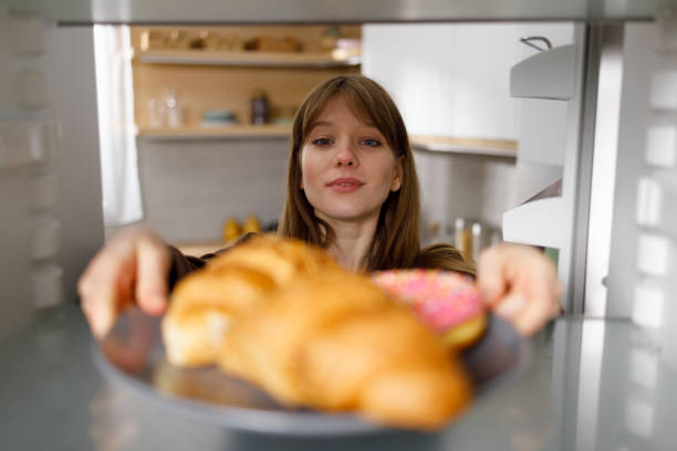 istock Young woman taking plate with croissants and donut from fridge 1401876007