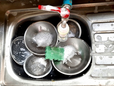 Washing Cooking utensils in kitchen sink after food preparation.