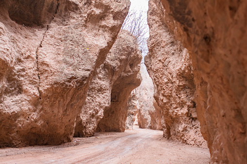 Narrow path between ember color canyon rocks under bright sunshine