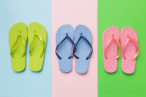 Stylish beach flip-flops on color background, top view