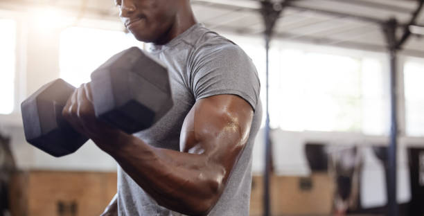 athlète afro-américain inconnu soulevant des haltères pendant l’entraînement du biceps curl bras au gymnase. homme noir fort, en forme, actif s’entraînant avec du poids dans un club de santé et de sport. routine d’exercices d’haltérophilie - men weight training african descent male photos et images de collection