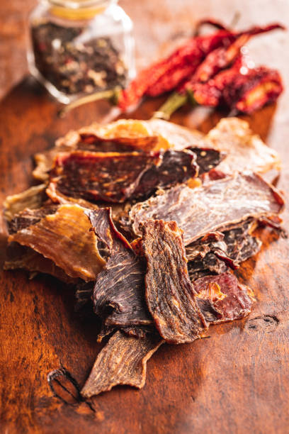 istock Beef jerky meat. Dried sliced meat on wooden table. 1401878655