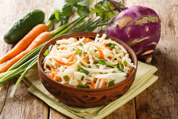 vegetarian vegetable salad of kohlrabi, carrots, cucumbers and green onions seasoned with oil close-up in a plate. horizontal - kohlrabi imagens e fotografias de stock