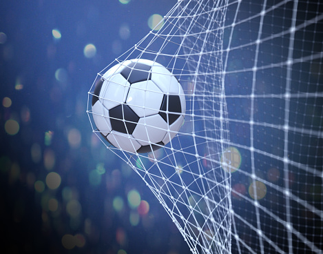 Soccer ball flying in the net. Fan background
