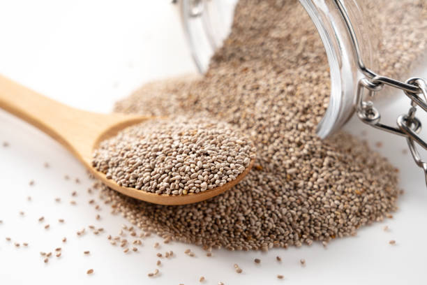 istock Wooden spoon, white chia seeds and glass container placed on white background. 1401888328