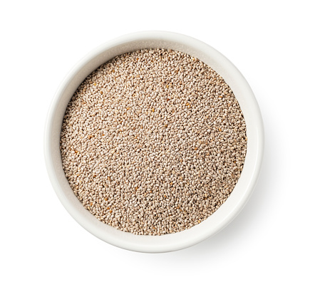 White chia seeds in a white bowl set against a white background. Close-up. View from directly above.