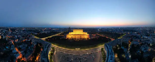Aerial drone panoramic view of Palace of the Parliament in Bucharest downtown at night, Romania. Multiple districts around