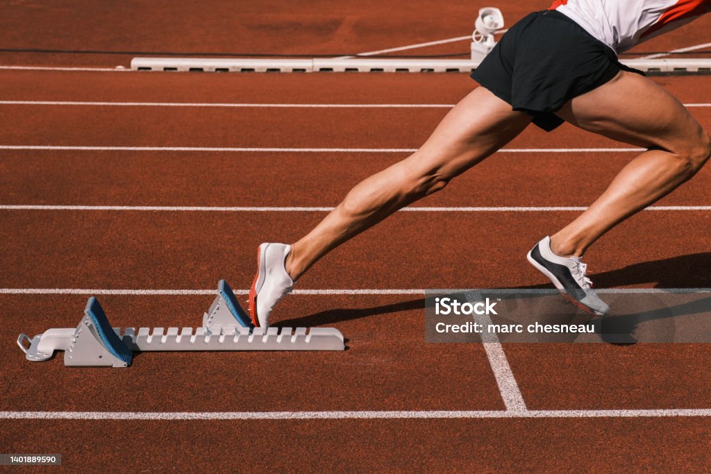 A rider at the start on a track A runner at the start on an athletics stadium track Track And Field Stock Photo