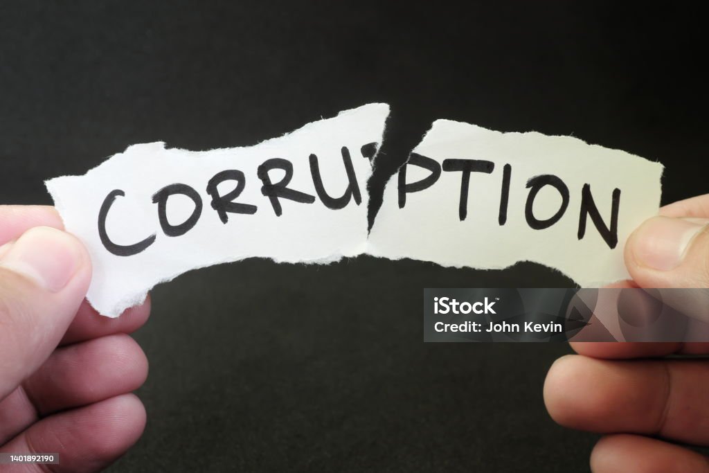 Stop and fight corruption concept. Human hand tearing a piece paper with written word corruption. Corruption Stock Photo