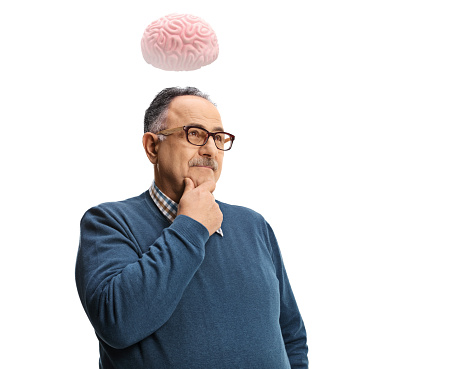 Pensive mature man standing and thinking with a human brain above his head isolated on white background