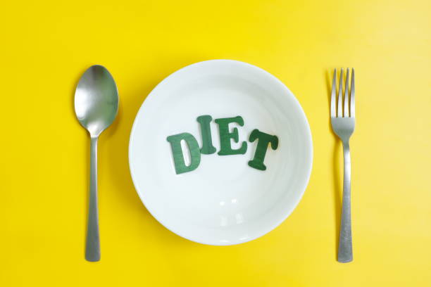istock Diet and nutrition concept. Fork, spoon and plate with DIET letters in bright yellow background. 1401892440