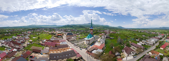 Aerial drone panoramic view of The Merry Cemetery in Sapanta, Romania. Church and multiple tombstones, residential buildings around it