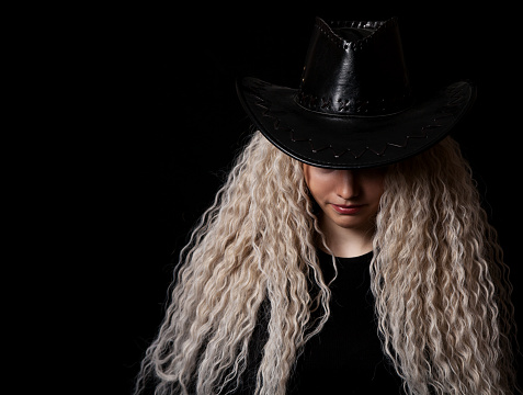 portrait of a young blonde girl with long curly hair in the studio on black background