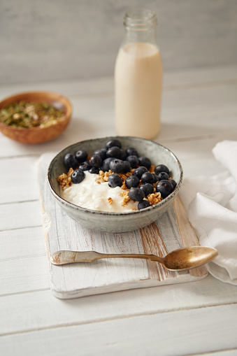 Granola with curd cheese and blueberries together with a milk bootle standing on a table