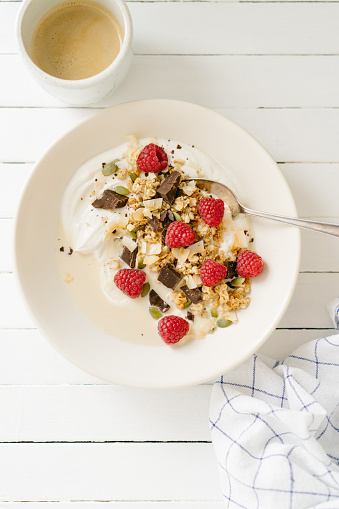 Granola with raspberries, chocolate and curd cheese standing on a white table