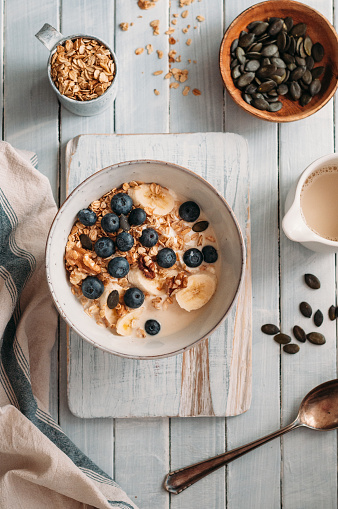 Oatmeal with blueberries, walnut, banana and oat drink in a bowl standing on a wooden table