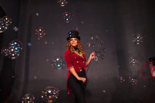 Female magician makes with soap bubbles show, an illusionist Woman magician with magic cane makes with soap bubbles show, an illusionist in theatrical clothes and hat. Female actress in stage costume. Theatrical performance and fun show. Copy space stage actress stock pictures, royalty-free photos & images