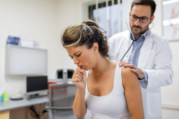 junge patientin in der klinik litt an einer lungenentzündung, sie hustet der arzt hört das keuchen in der lunge mit einem stethoskop ab. - husten stock-fotos und bilder