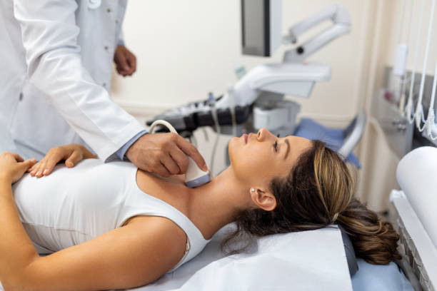 doctor making ultrasound of thyroid gland to woman patient in clinic. diagnosis and treatment of autoimmune thyroiditis concept - ultrasound cancer healthcare and medicine thyroid gland imagens e fotografias de stock