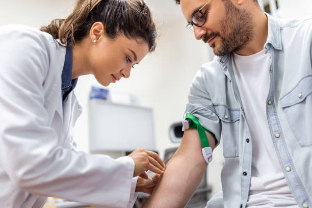 Friendly hospital phlebotomist collecting blood sample from patient in lab. Preparation for blood test by female doctor medical uniform on the table in white bright room Friendly hospital phlebotomist collecting blood sample from patient in lab. Preparation for blood test by female doctor medical uniform on the table in white bright room blood test stock pictures, royalty-free photos & images