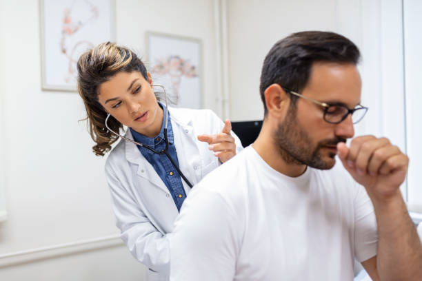 une femme médecin de la clinique effectue l’auscultation des poumons d’un patient présentant des symptômes de coronavirus ou de pneumonie. il tousse le médecin écoute la respiration sifflante dans les poumons - primary care photos et images de collection