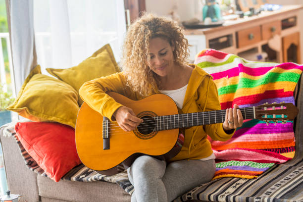 istock Smiling Woman Playing Guitar At Home 1401899146