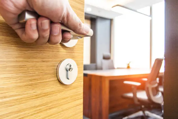 Photo of Hand pushing open the wooden door of the office