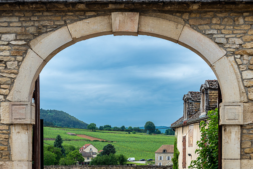 A view through a decorative, arched, doorway towards the distant vineyards of the Cote d’Or region.